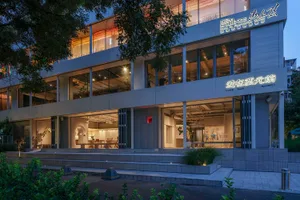 Modern restaurant exterior with concrete materials and illuminated interior lights.