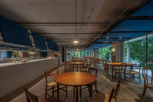 A modern restaurant dining area with concrete floors and wooden tables and chairs.
