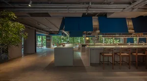 A modern restaurant kitchen with tile flooring and blue pendant lights hanging above a kitchen island.