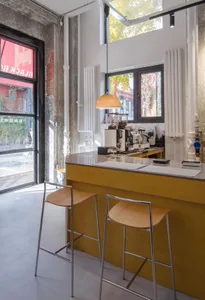 Interior view of a coffee shop featuring a wooden counter bar, high stools, and a modern coffee machine.