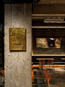 An indoor space with a modern industrial design, featuring a concrete pillar with a metallic plaque displaying the name of th
