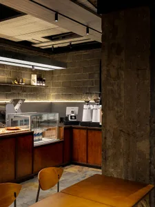 Industrial-style cafe interior featuring concrete walls, wooden tables, and metal coffee grinders.