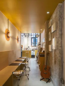An industrial-style music store with wooden, concrete, and brick walls, featuring musical instruments and a seating area.