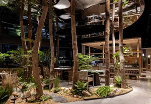 Industrial-style restaurant interior with green plants and natural elements.