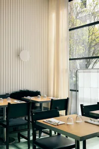An image of an industrial-style restaurant interior with wooden tables, glassware, and metal chairs.