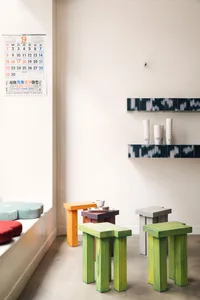A minimalist cafe interior featuring various wooden stools in different colors.