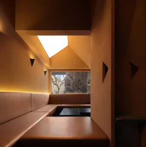 Leather booths in modern restaurant setting, illuminated by warm lighting from a skylight.
