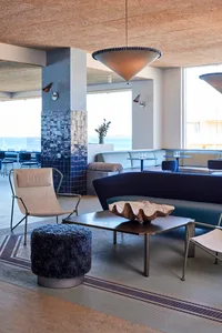 Modern hotel lobby featuring metal, glass, leather, and wooden elements.