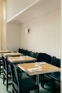 A modern restaurant interior with wooden tables and chairs.