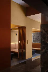 Interior of a modern restaurant featuring leather seating, marble accents, and concrete structural elements.