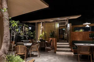 Modern restaurant interior with concrete flooring, wooden tables, and bamboo decor