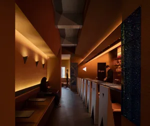 A modern restaurant interior with brick and concrete walls, sleek furniture, and a bar.