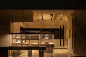 A minimalist restaurant interior featuring glass, concrete, and metal elements.