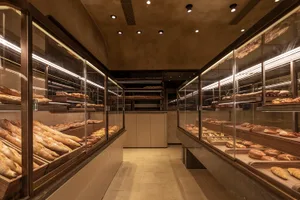 Modern bakery interior with glass display counters showcasing an assortment of freshly baked breads and pastries.