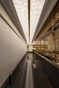 A modern interior design of a corridor featuring ceramic tiles and gold brass materials.