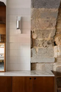 Modern kitchen featuring white tiled walls and concrete elements.