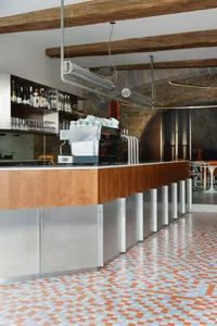 Industrial design cafe bar with metal counter, wooden seating, and stone walls.
