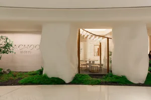 A minimalist coffee shop interior featuring white stone walls and a green plant.