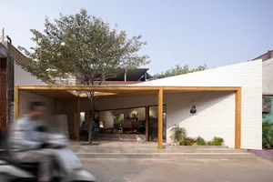 A minimalist restaurant exterior with white paneled walls and a wooden canopy.