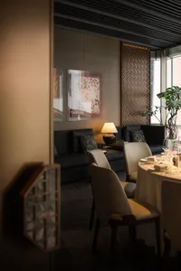 A modern restaurant dining area with fabric seating, glass panels, and metal accents.
