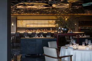 A modern restaurant bar with dark wood and stone finishes, featuring a luxurious interior design.