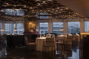 Modern restaurant interior with metal ceiling and round tables.