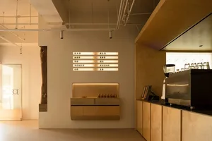 Minimalist design featuring wooden cabinets, concrete walls, and metal accents within a coffee shop interior.