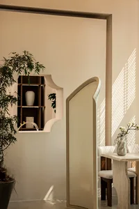 A well-lit, neutral-toned home office space with a wooden table, chairs, and a potted plant.