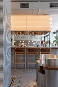 A modern restaurant bar counter featuring a tile top and minimalist design.