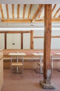 A modern restaurant interior with wooden tables, chairs, and built-in seating.