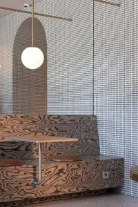 A modern restaurant setting featuring a wooden booth with a grid-patterned wall, designed to evoke an industrial aesthetic.