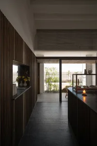 A minimalist interior space featuring wooden paneling, with plants and a candle in the foreground.
