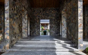 Modern entrance featuring stone walls, steps leading to an open space.