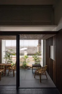 Cafe interior with wooden walls, plants, and rattan furniture.
