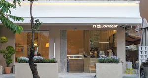 Outdoor seating area of a modern coffee shop with concrete and glass elements.