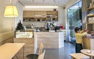 A modern coffee shop with wooden interior and a small boy reaching for something