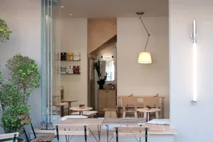A modern minimalist cafe interior featuring wooden furniture and neutral tones.