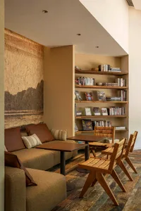 A living room with modern furniture, wooden bookshelves, and a cozy reading area.