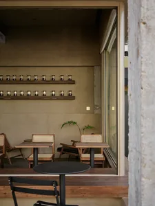 A modern industrial coffee shop interior with concrete walls and tables, featuring wooden chairs and a minimalist design.