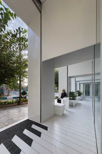 A modern lobby with white concrete flooring and minimalist design elements.