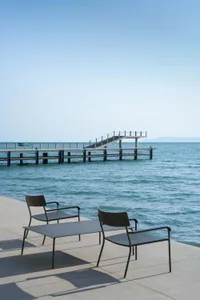 A modern oceanfront lounge featuring metal furniture and a view of the sea.
