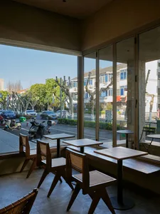 A cafe interior with wooden tables, glass walls, and a view of the street.