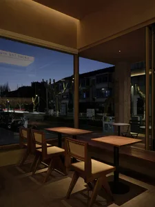 A cozy restaurant interior with wooden tables and chairs, large windows, and a comfortable atmosphere.