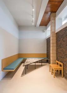 A modern coffee shop interior featuring wooden furniture and a triangular mosaic table.