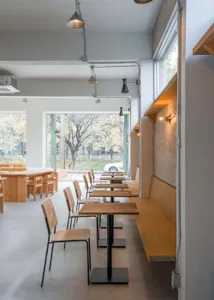 A minimalist cafe interior with wooden tables, chairs, and benches.