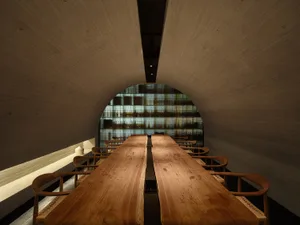 A modern restaurant interior featuring wooden tables and chairs in a tunnel-like space