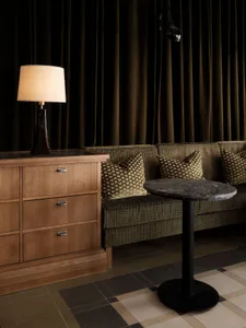 Modern living room with wood cabinet, marble table, green sofa, and fabric pillows.