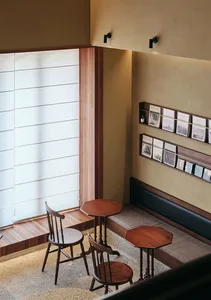 A cozy coffee shop interior with wooden furniture and a seating area by a large window.