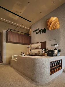 Modern coffee shop with a sleek concrete countertop featuring a coffee-making station and coffee bags on display.