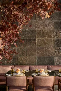 Outdoor dining area with metallic tiles and fabric upholstery, featuring a glass table.
